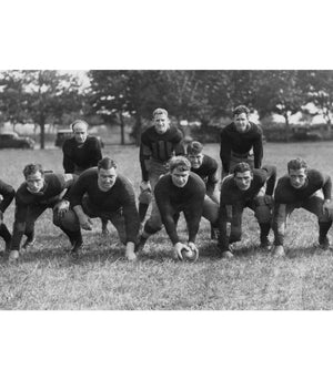 black and white image of 1940's football players crouching on the field